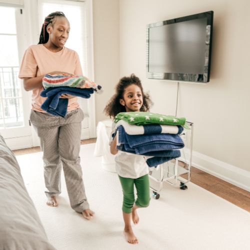 Mom and daughter carrying folded laundry together